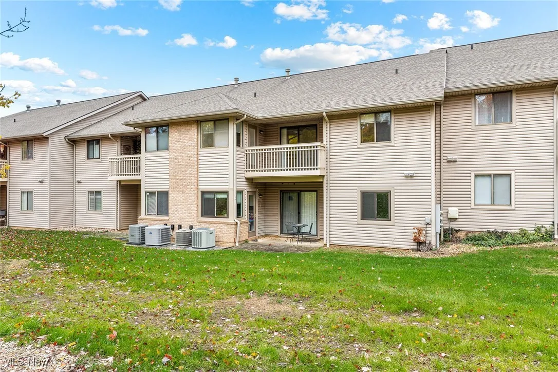 Rear view of house with a patio, roof with shingles, a balcony, and a yard