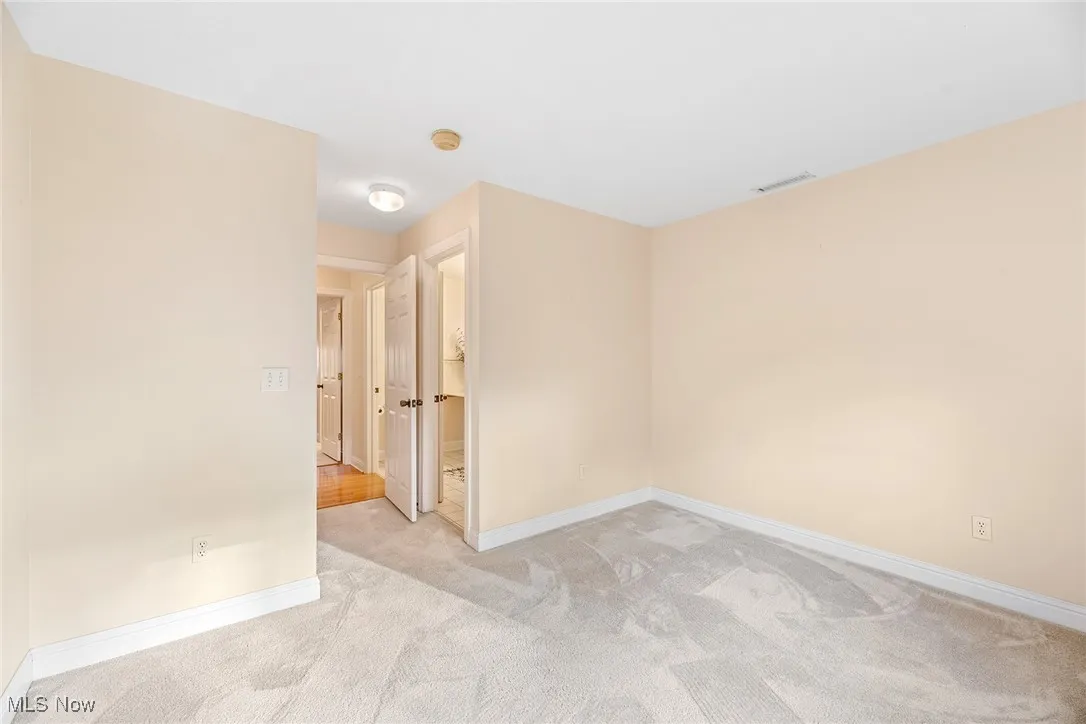 Unfurnished room featuring light carpet and baseboards