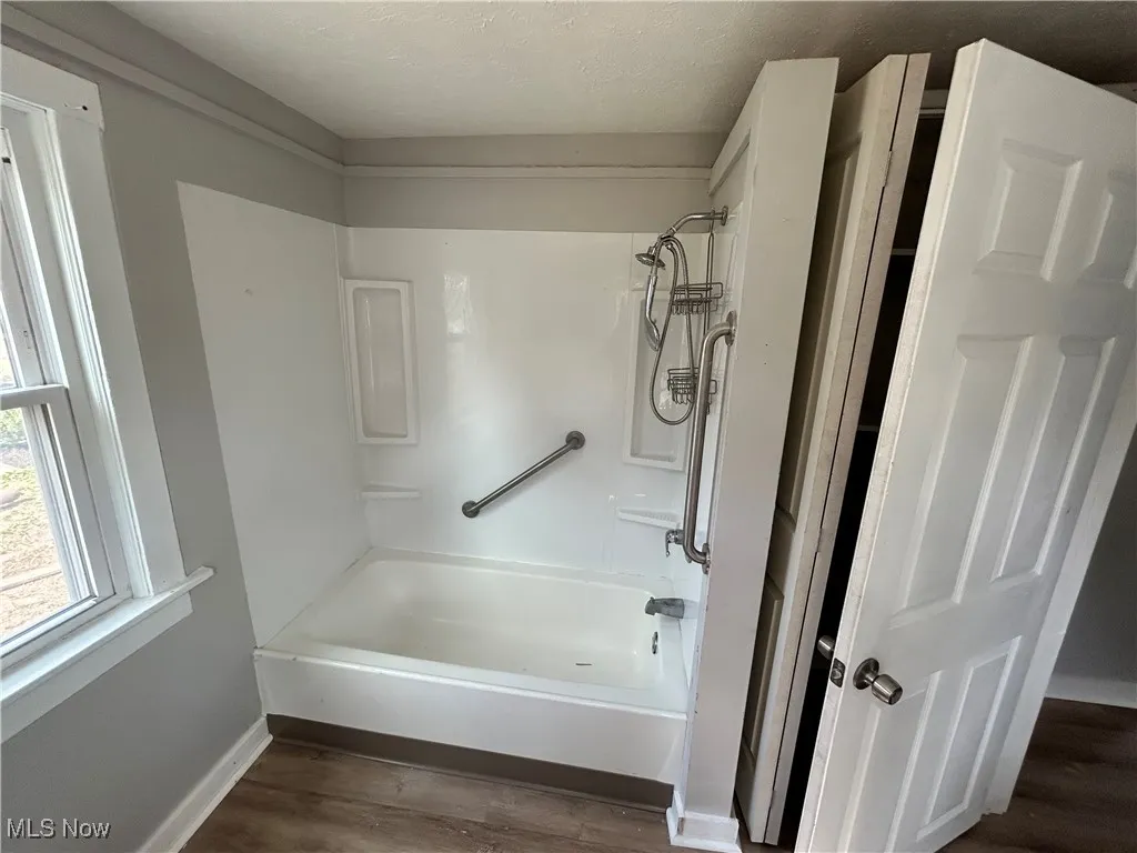 Bathroom featuring dark wood-type flooring, bathtub / shower combination, and a textured ceiling