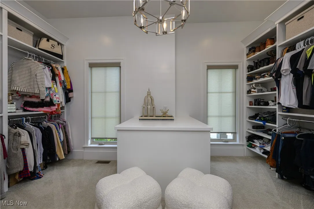 Walk in closet with light carpet and a chandelier