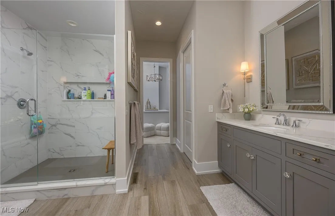 Full bathroom featuring vanity, a marble finish shower, light wood-style flooring, and recessed lighting