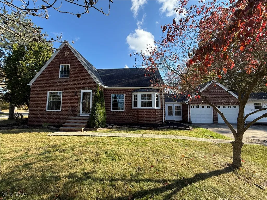View of front of home featuring brick siding, a front yard, a garage, and driveway