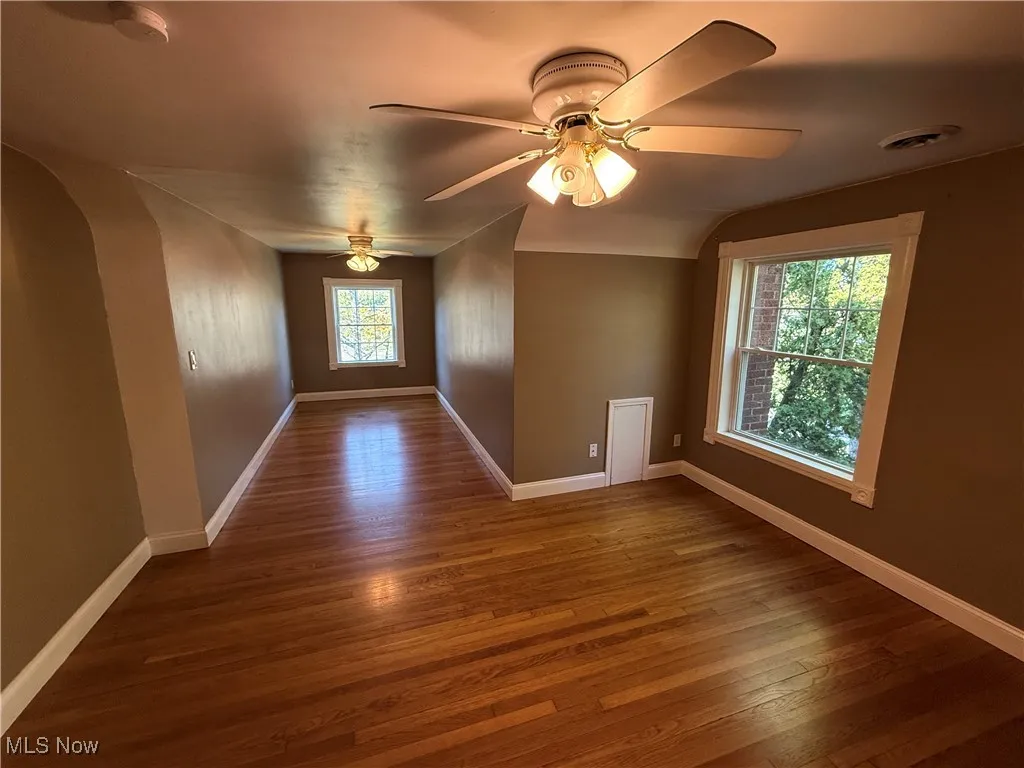 Spare room with dark wood-style floors, arched walkways, and ceiling fan