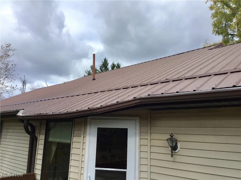Exterior view of gutters, a metal roof, and a downspout