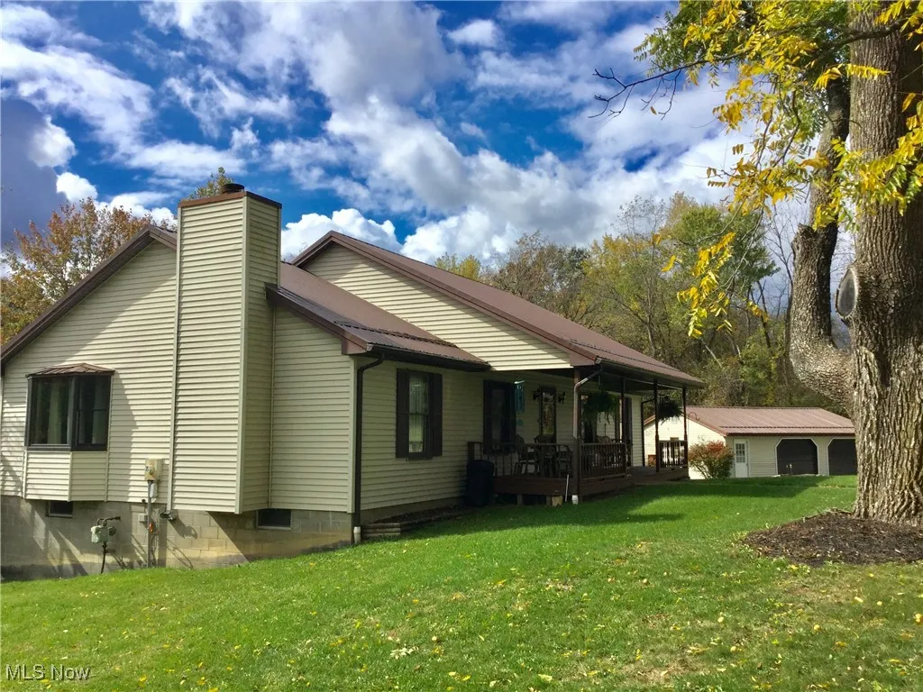 Rear view of property featuring a yard, a deck, and a chimney