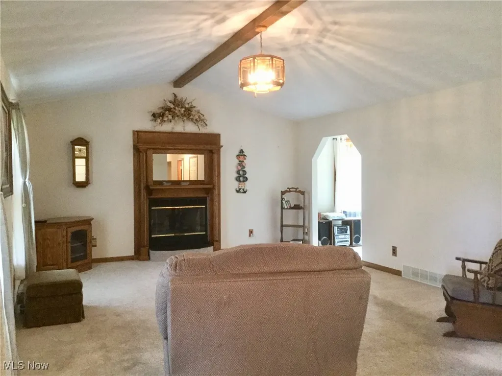 Living area with light colored carpet and arched walkways