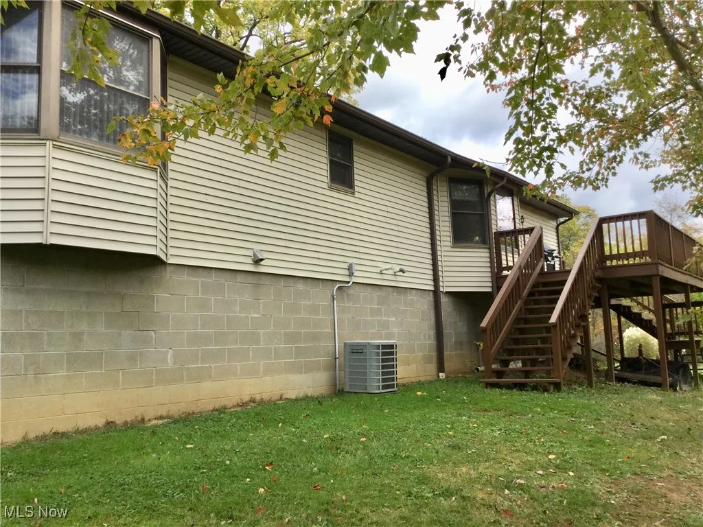 Rear view of house featuring stairs, a yard, and a wooden deck