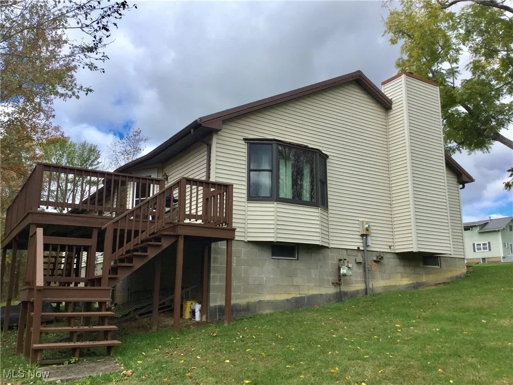 View of home's exterior with a deck, stairs, a chimney, and a yard