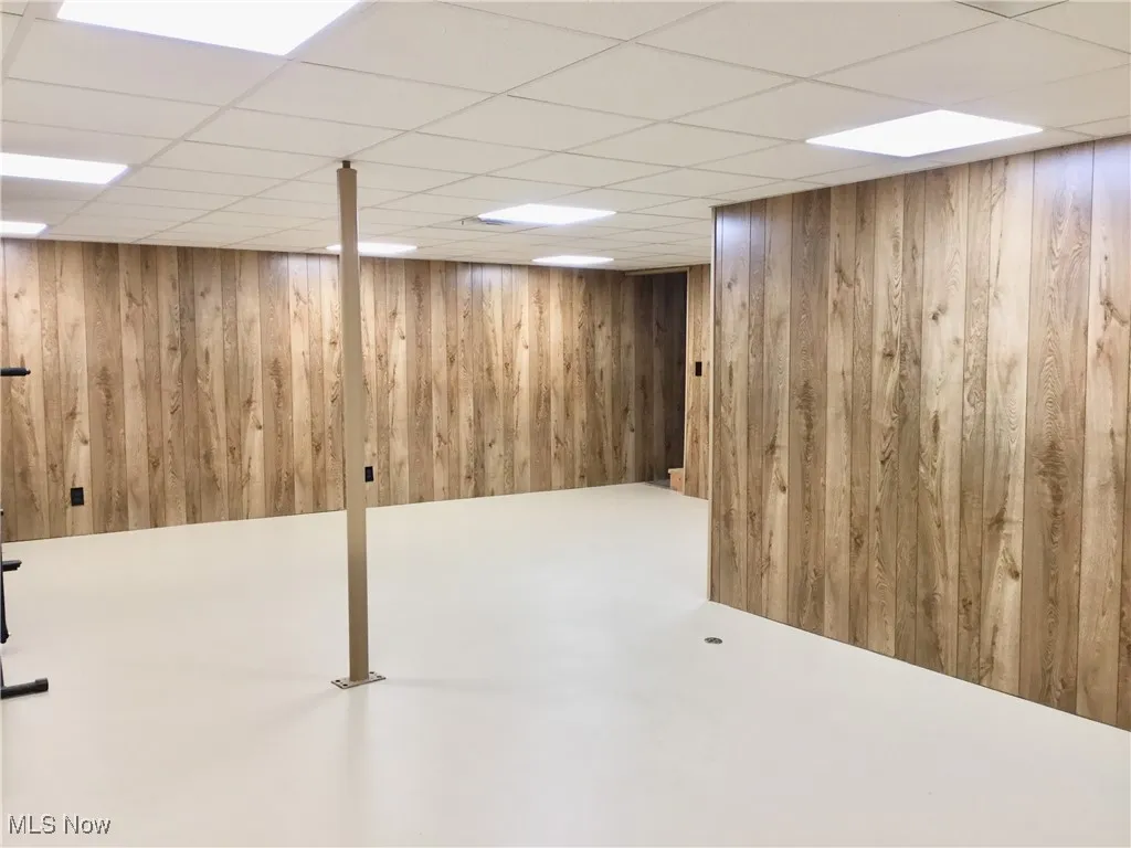 Finished below grade area with a paneled ceiling and wooden walls