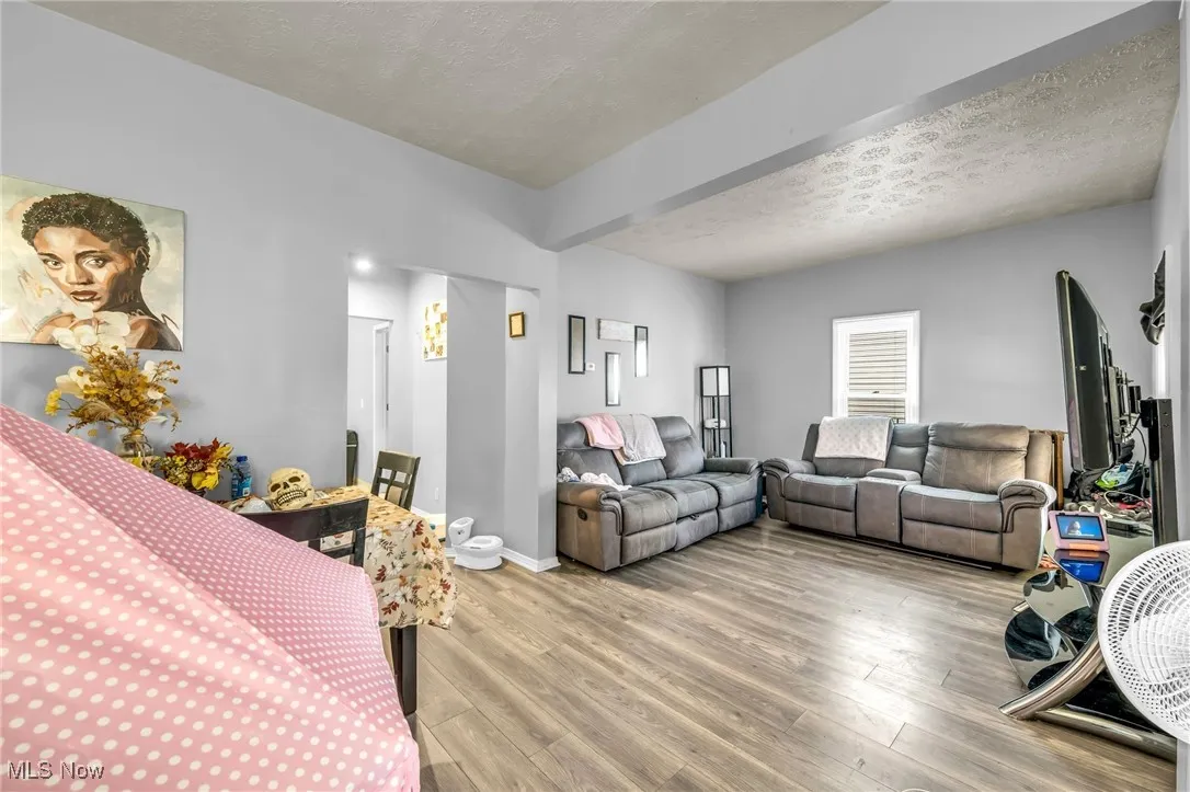 Living room with a textured ceiling, wood finished floors, and beamed ceiling