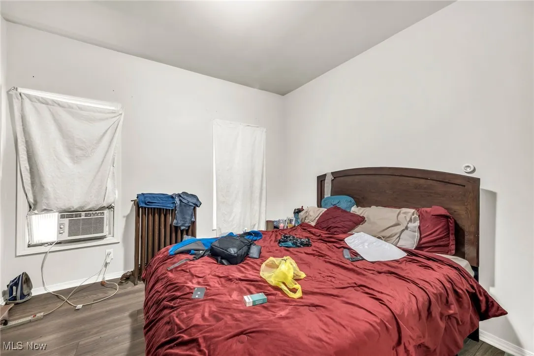 Bedroom featuring wood finished floors, cooling unit, and radiator heating unit