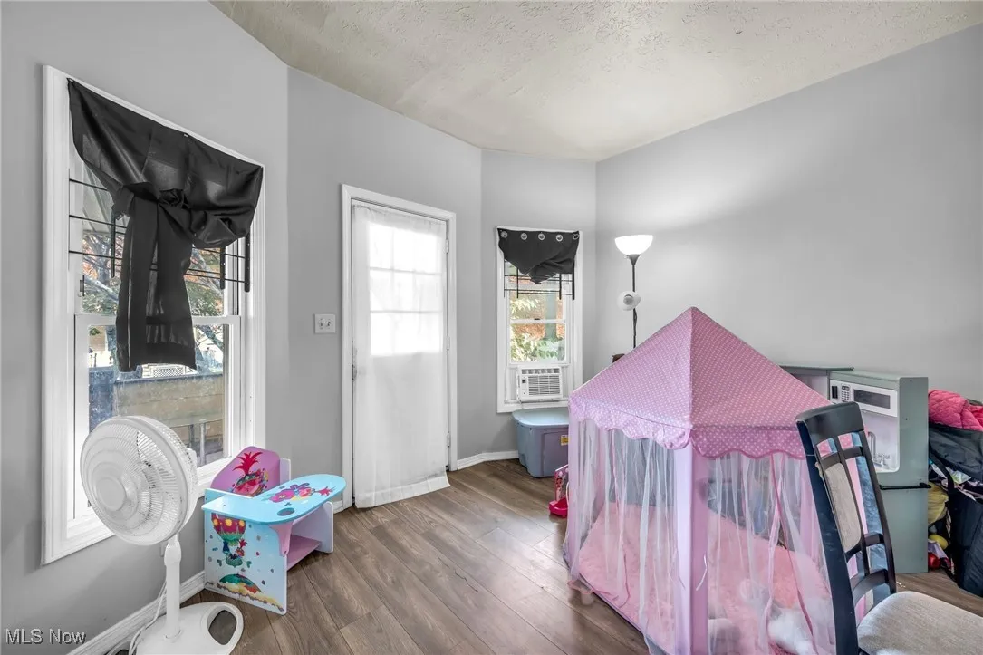 Bedroom with wood finished floors, a textured ceiling, and cooling unit