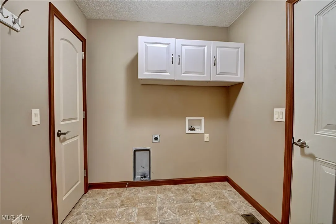 Laundry room with cabinet space, electric dryer hookup, hookup for a washing machine, and a textured ceiling