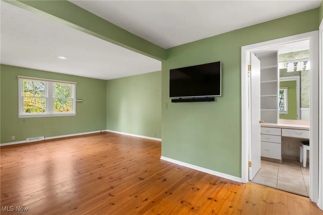 Unfurnished living room featuring hardwood / wood-style floors and baseboards