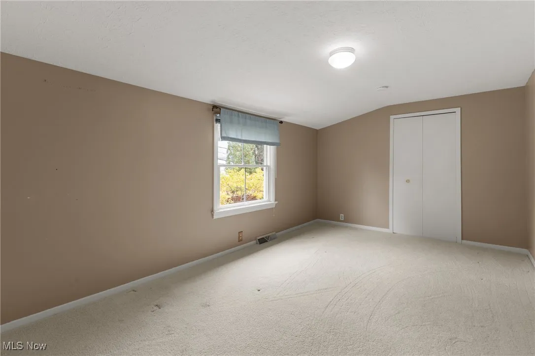 Unfurnished bedroom featuring a closet, carpet flooring, and lofted ceiling