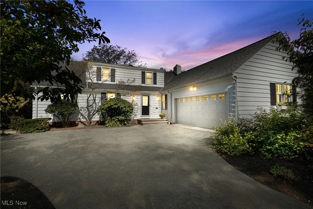 Traditional home with driveway, an attached garage, and a shingled roof