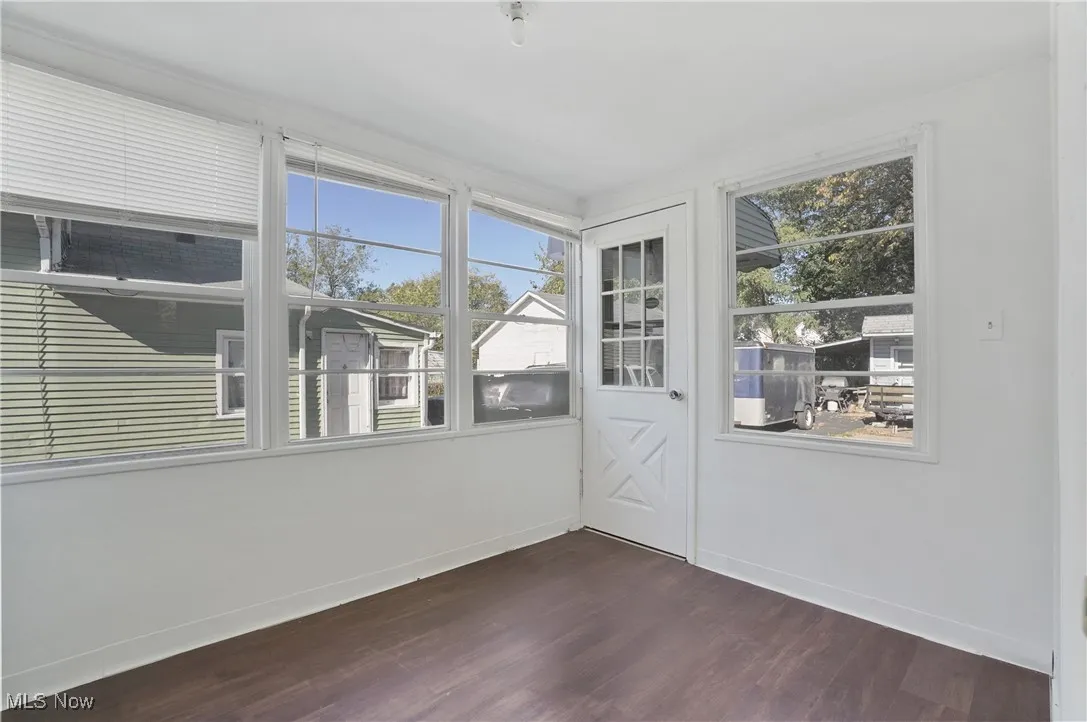 Unfurnished sunroom featuring wood finished floors and baseboards