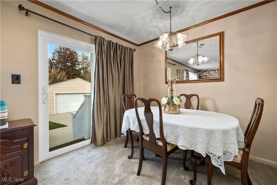 Dining space featuring light carpet, crown molding, and a chandelier
