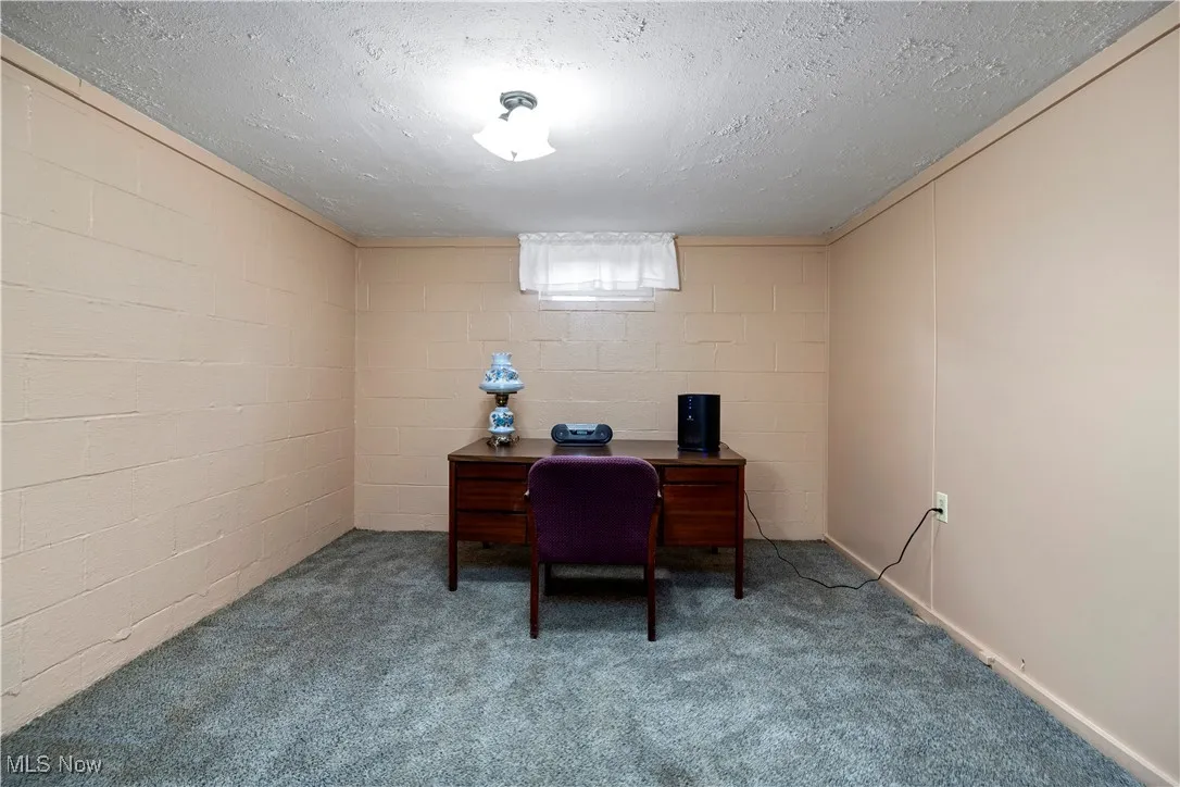 Carpeted office with concrete block wall and a textured ceiling