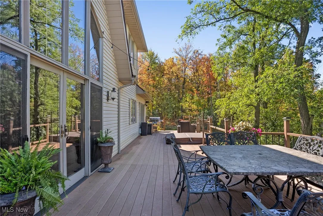 Deck featuring outdoor dining space and view of wooded area