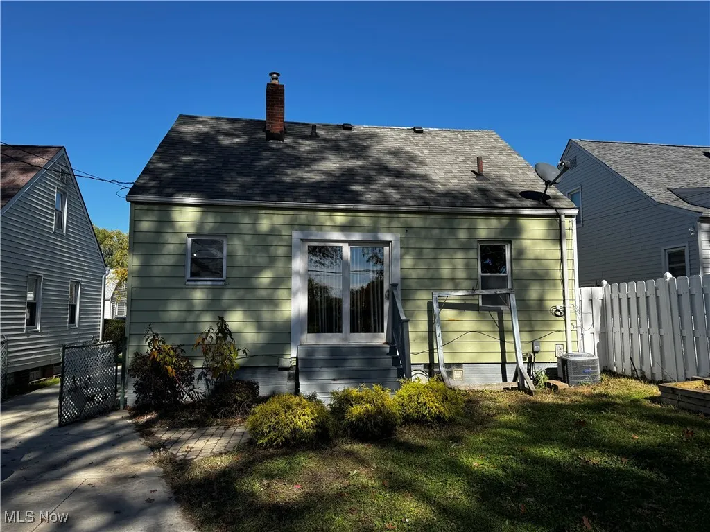 Back of property featuring a chimney and a shingled roof