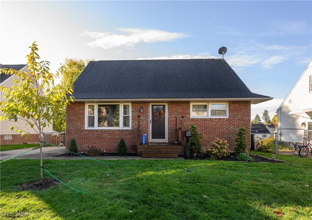 View of front facade featuring brick siding, a shingled roof, and a gate