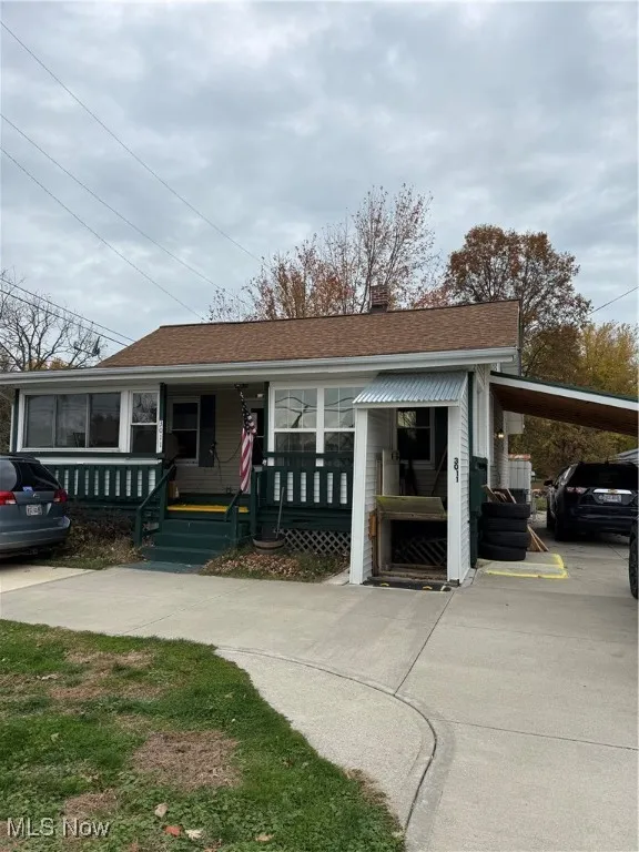 View of front facade featuring covered porch, roof with shingles, and a chimney