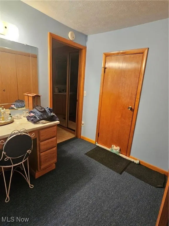 Office space featuring a textured ceiling and dark carpet