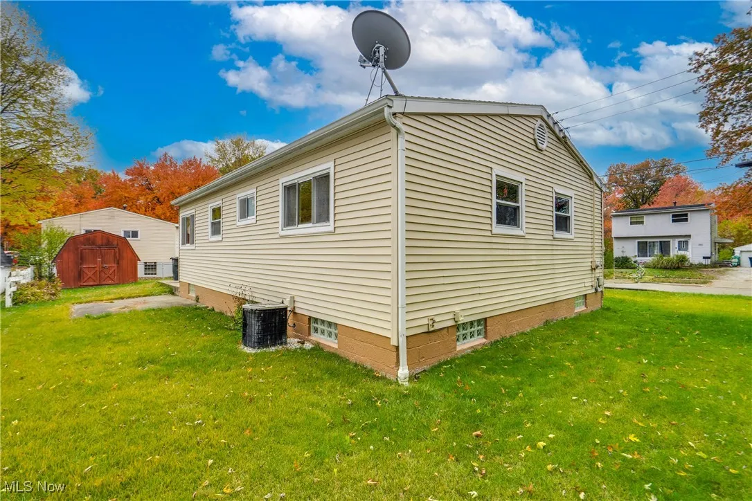 View of property exterior with a yard and a shed
