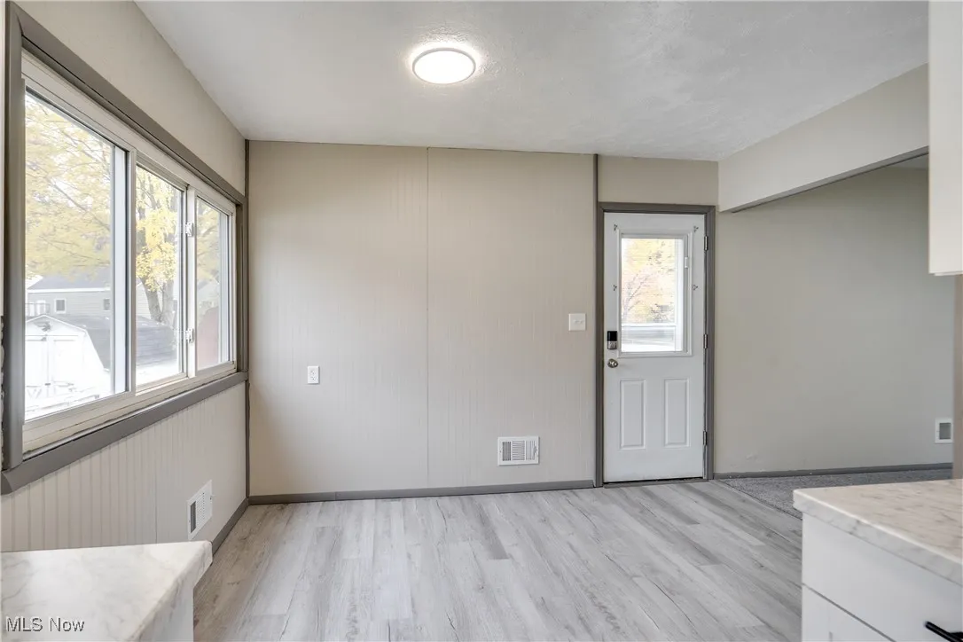 Unfurnished dining area with light wood-style flooring and a textured ceiling