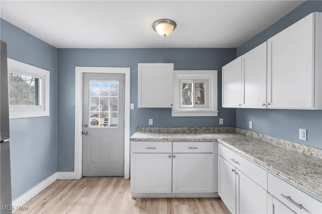 Kitchen featuring white cabinets, light wood finished floors, and freestanding refrigerator