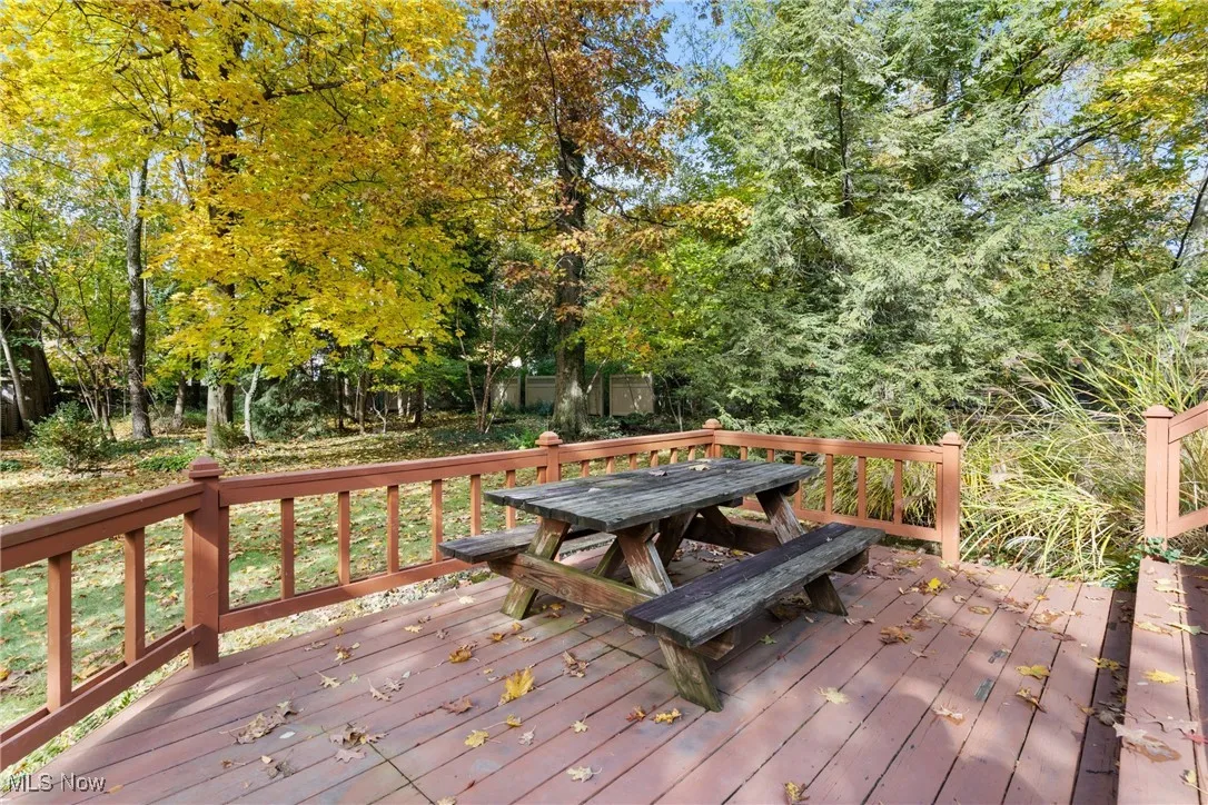 Wooden deck featuring outdoor dining space and view of wooded area