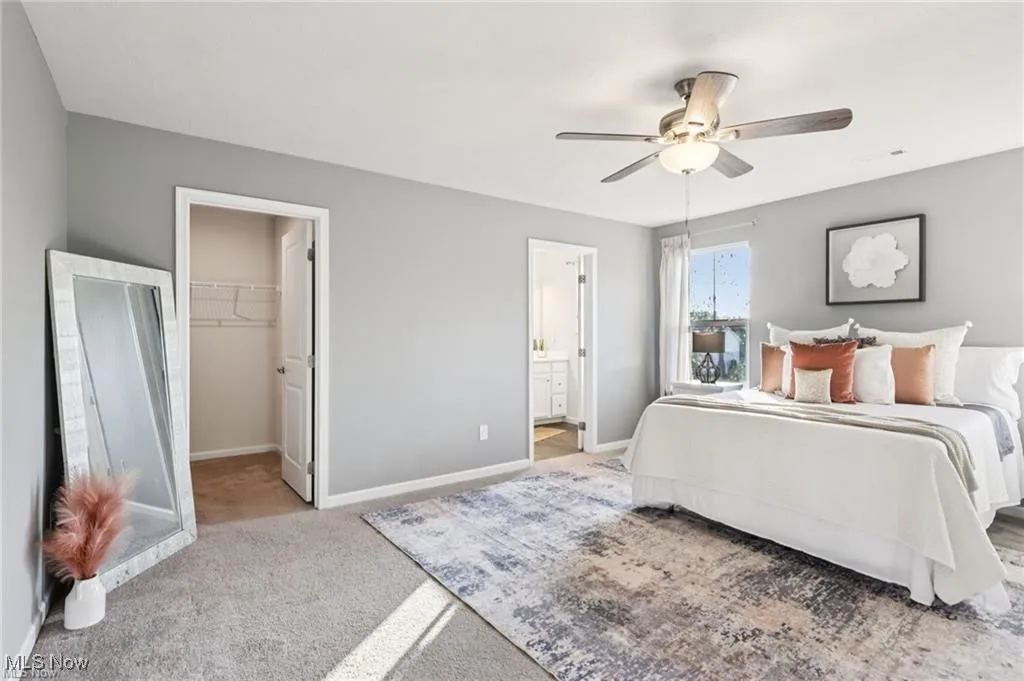 Bedroom with a walk in closet, light carpet, and ceiling fan