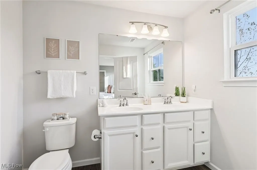 Full bathroom featuring double vanity and baseboards