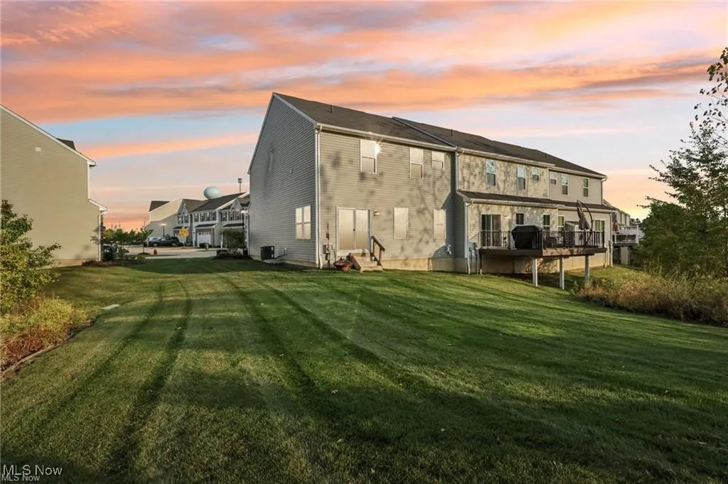 Back of house with a lawn and a wooden deck