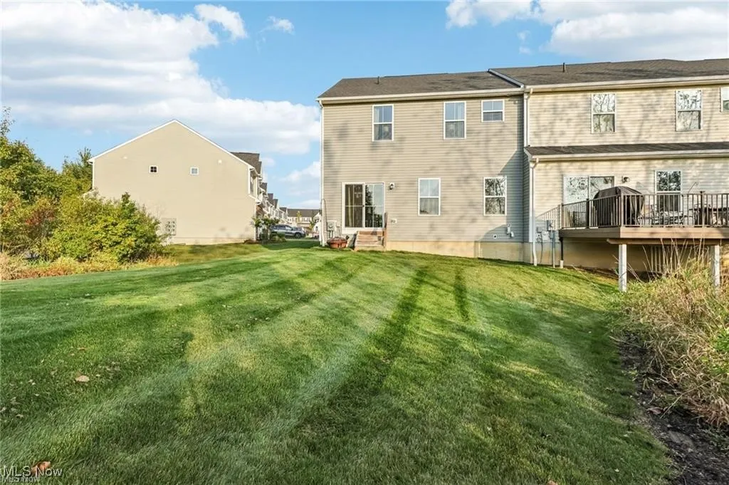 Rear view of house featuring a lawn and a wooden deck