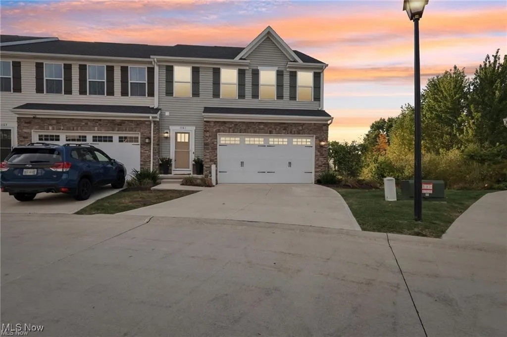 View of front of house with driveway, stone siding, and an attached garage