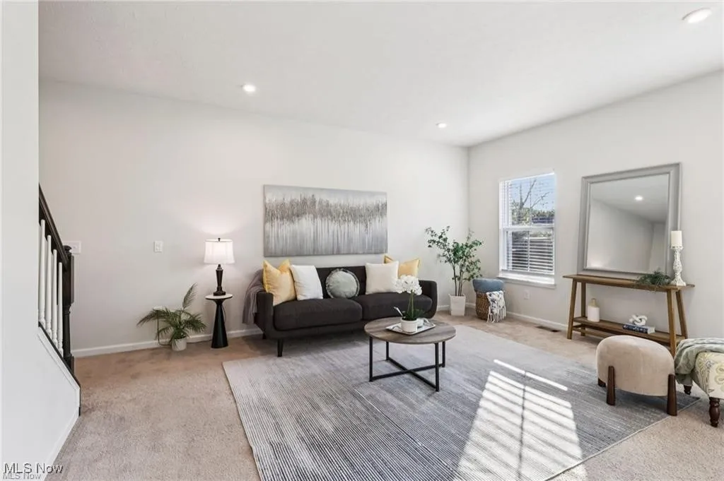 Living area with carpet, recessed lighting, and stairway
