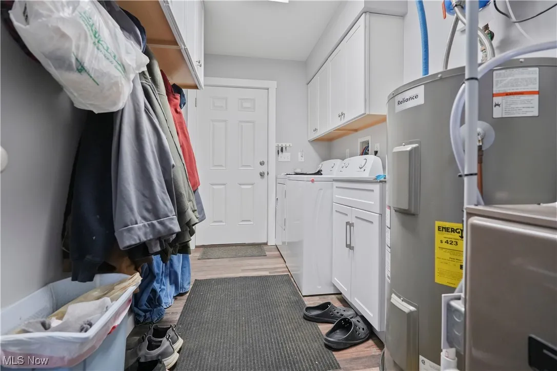 Washroom featuring electric water heater, light wood-style floors, and cabinet space