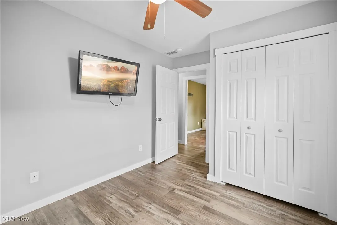 Unfurnished bedroom featuring light wood finished floors, a closet, and ceiling fan