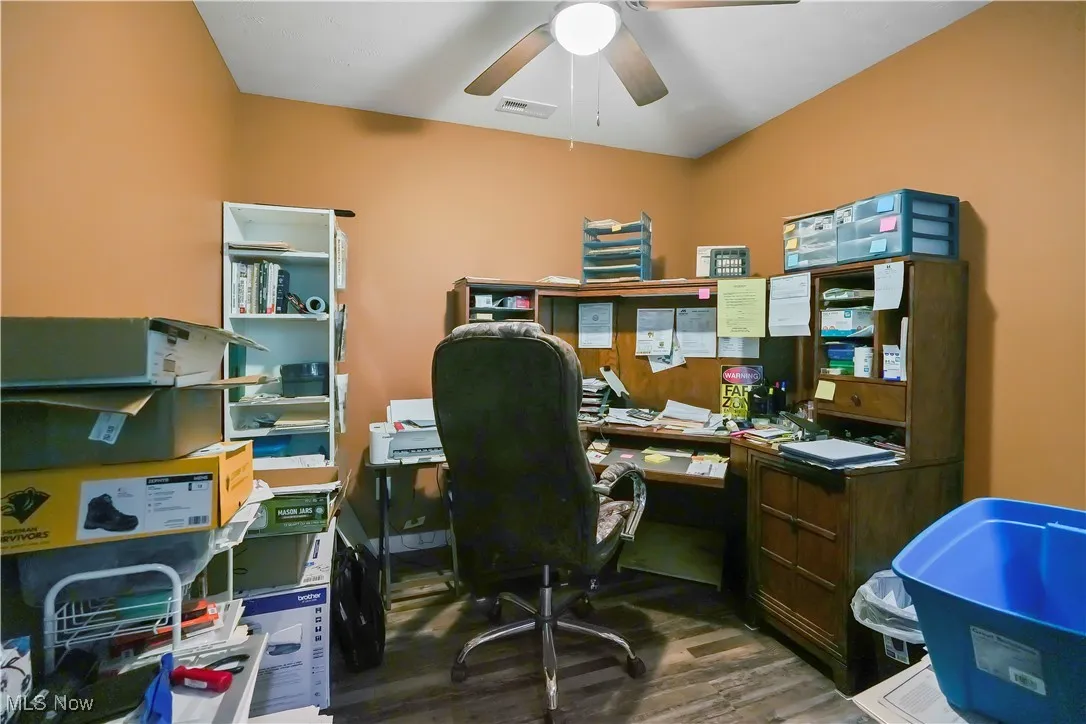 Office with dark wood-style floors and a ceiling fan