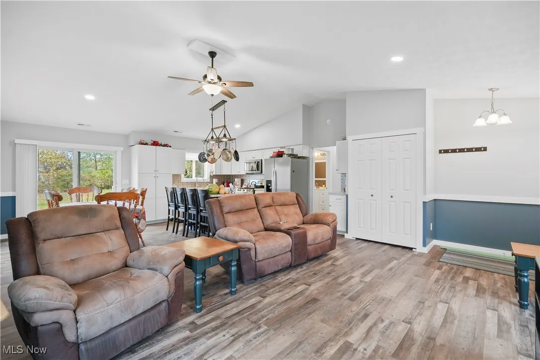 Living area featuring a chandelier, light wood-style floors, recessed lighting, a ceiling fan, and high vaulted ceiling