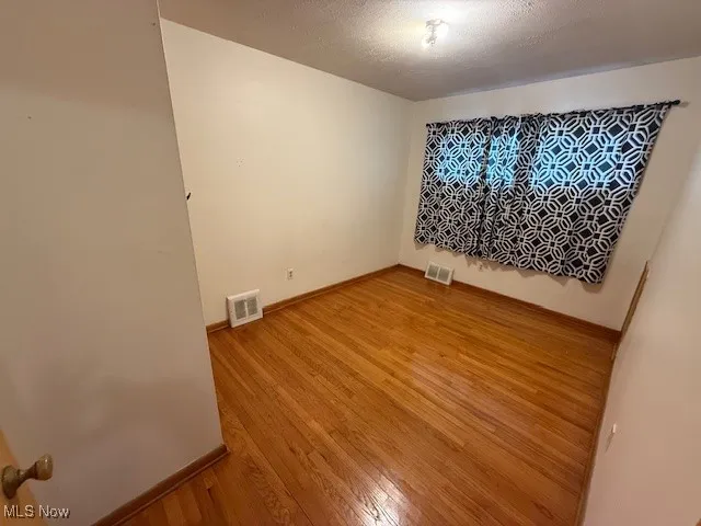 Spare room featuring a textured ceiling and light wood finished floors