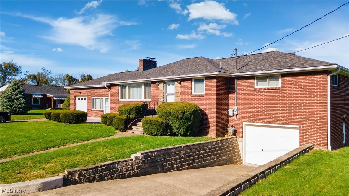 Ranch-style home with a front yard, brick siding, a garage, and a chimney