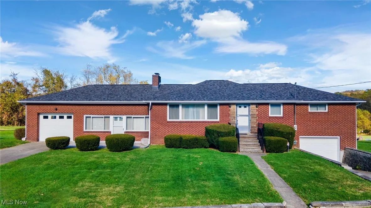 Ranch-style house featuring a garage, a front lawn, concrete driveway, and a chimney