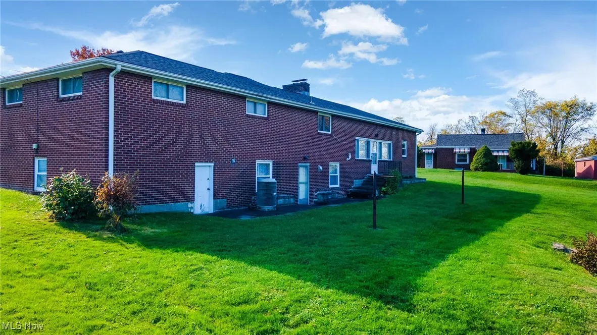 View of side of home featuring brick siding, a chimney, and a yard