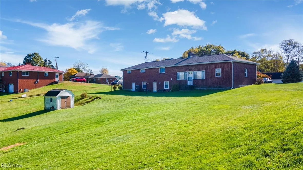 Back of property featuring a storage shed and a lawn
