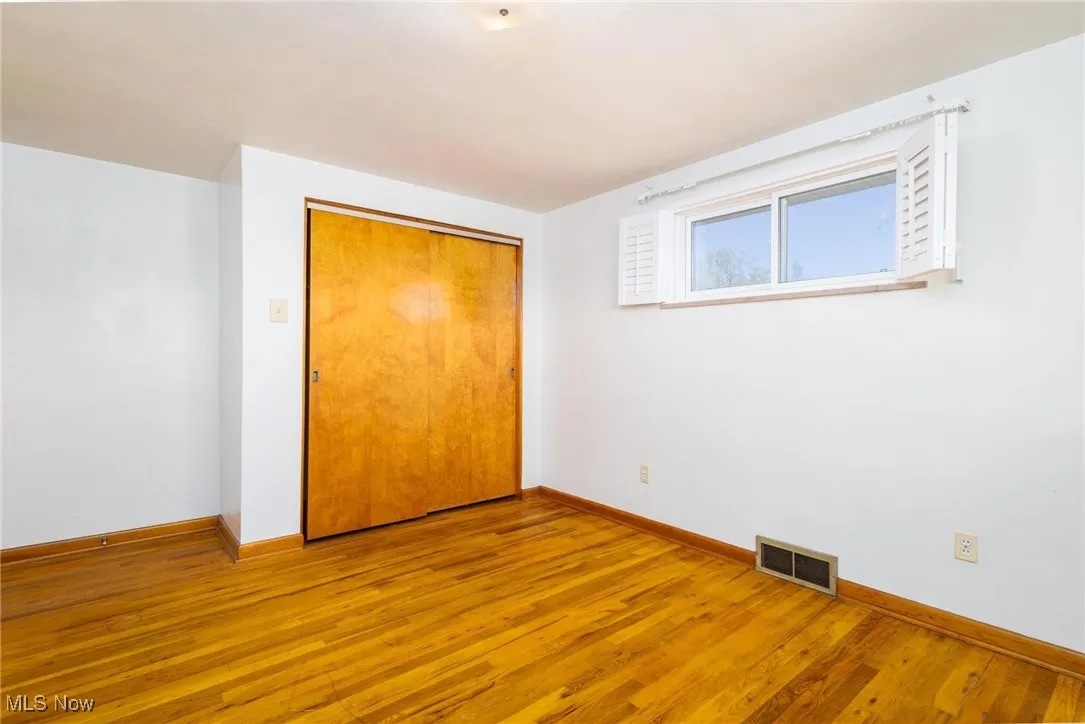 Unfurnished bedroom with wood finished floors and a closet