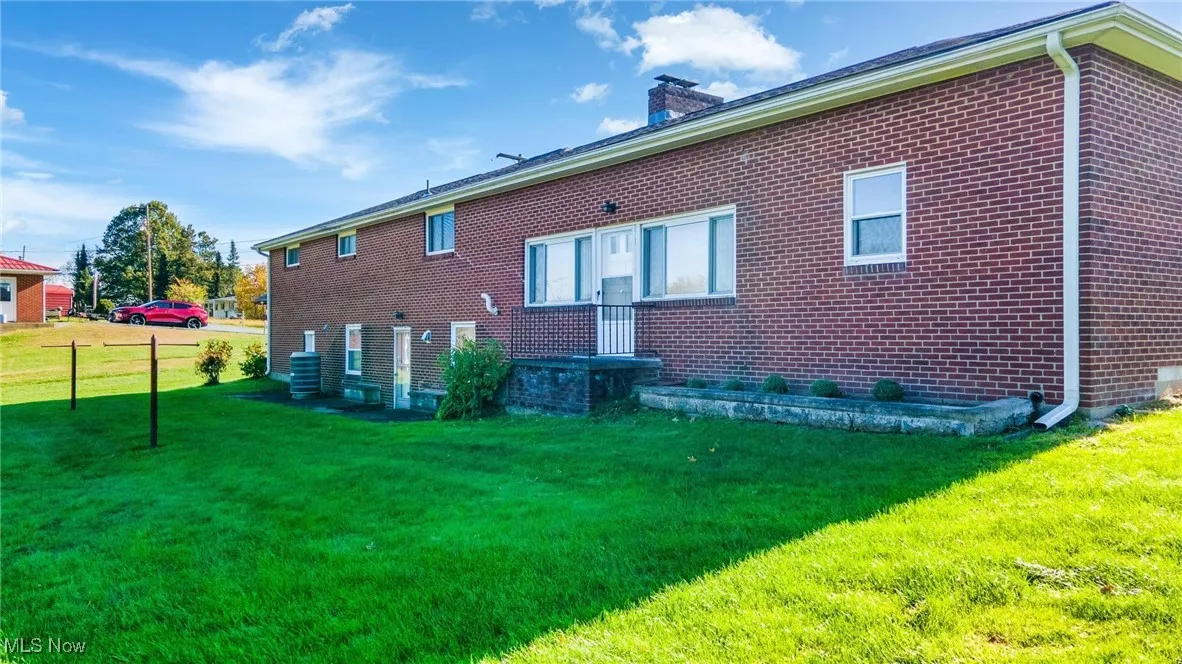 Back of property with brick siding, a yard, and a chimney