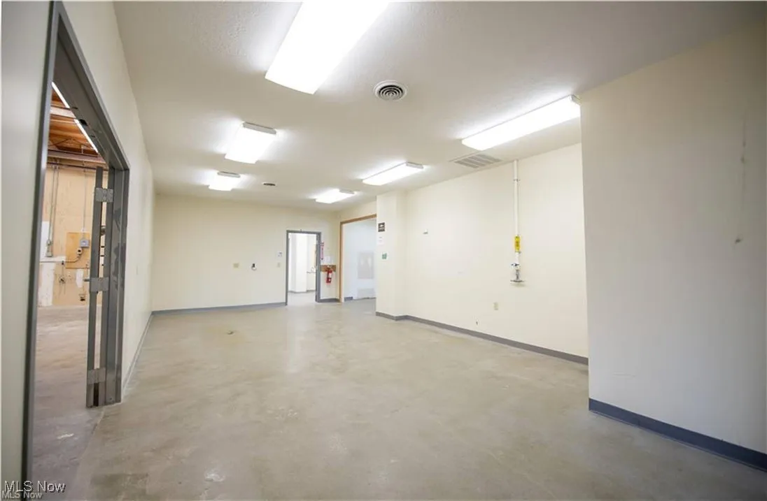 Empty room featuring concrete flooring and baseboards